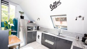 Une cuisine moderne dotée d’un lave-linge encastré, d’un espace dédié à la préparation du café et offrant une vue sur l’extérieur.