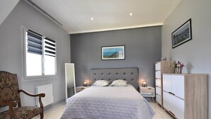 Une chambre à coucher avec un lit, une chaise, une commode et un tableau accroché au mur.