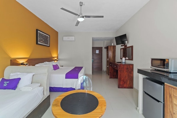 A hotel room with a bed, a desk, a microwave, and a television.