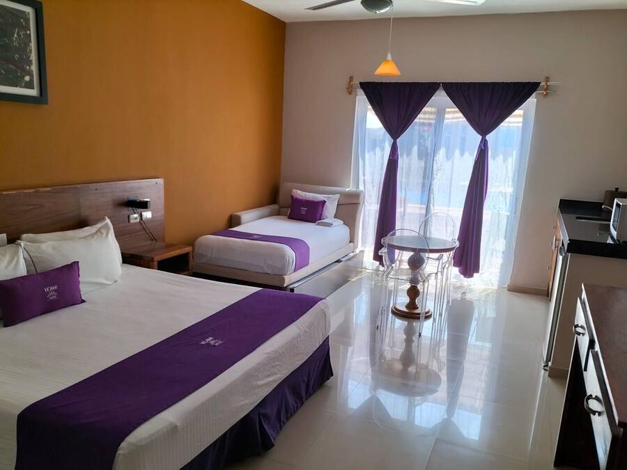 A hotel room with two beds, a dining table, and a kitchenette.