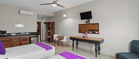 Una habitación de hotel con dos camas, un escritorio, una silla, un televisor y un ventilador de techo.