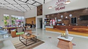 Um saguão de hotel com balcão de recepção, área de estar e vista para o exterior.