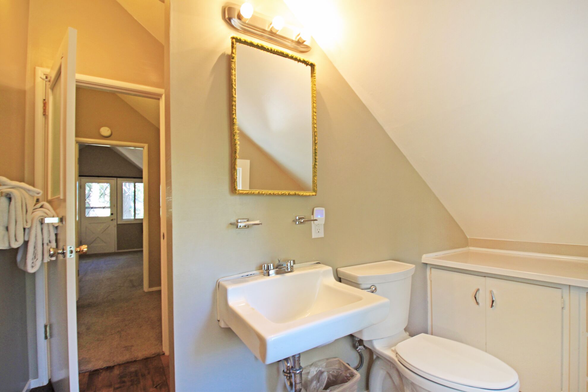 A bathroom with a white sink, two toilets, a mirror, and a towel rack.