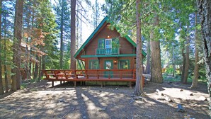 A cabin with a balcony, surrounded by trees.