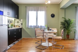 Una cocina moderna con armarios oscuros, salpicadero de azulejos y un comedor con una mesa redonda y dos sillas.