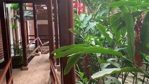 A wooden staircase leading to a covered area with a brick wall and a view of lush green plants. - Hotel Rio Huallaga (Yurimaguas)