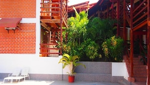 A swimming pool with a red brick wall, a wooden staircase, and a potted plant. - Hotel Rio Huallaga (Yurimaguas)