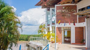 A hotel with a name sign, outdoor seating, and palm trees. - Hotel Rio Huallaga (Yurimaguas)
