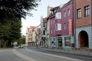 Una calle con una hilera de edificios, incluyendo un hotel con un letrero.