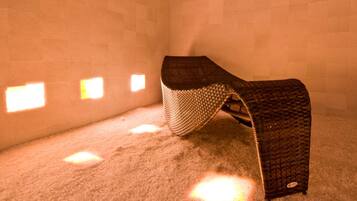 A room with a single bed, a textured blanket, and a wall with small square windows.