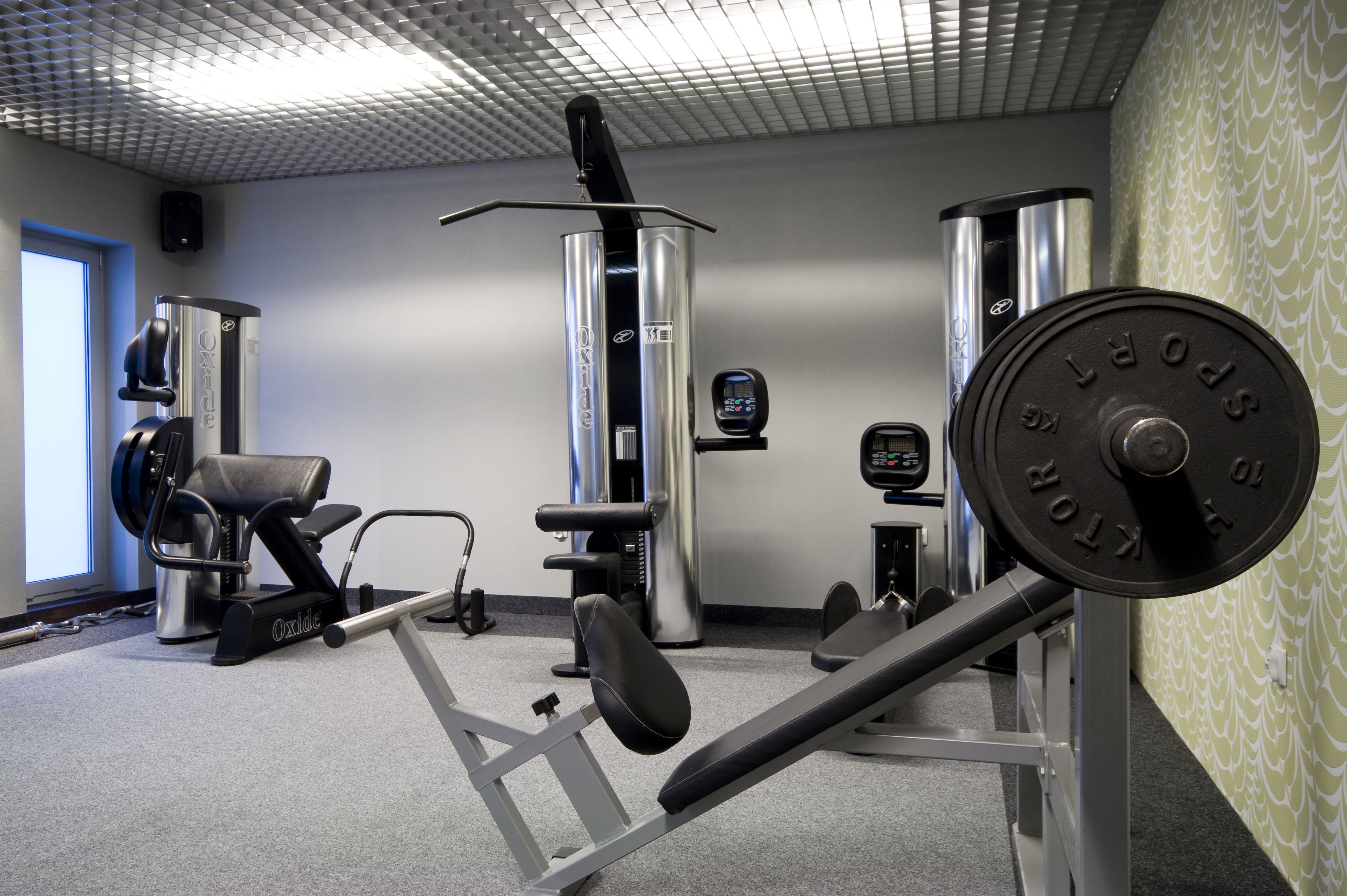 A gym with exercise equipment, a weight bench, and a wall-mounted speaker.