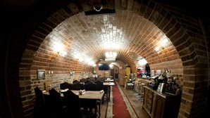 A brick-walled dining area with tables and chairs, a bar area with stools, and a chandelier. - Hotel Warmia Spa (Braniewo)