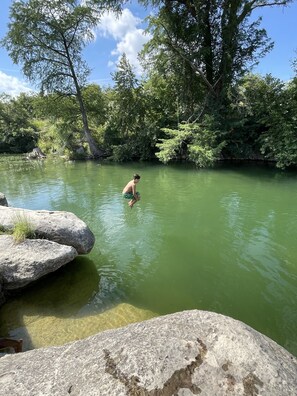 Un paysage naturel avec une personne dans l’eau, entourée de rochers et d’arbres.