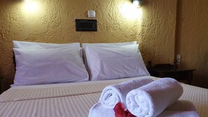 Una habitación de hotel con cama, almohadas, un panel de control y una mesita de noche.
