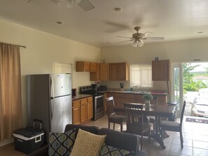 A compact kitchen with a refrigerator, microwave, stove, and wooden cabinets. - Baldwin Camp Rental Properties House #2, is located in North Caicos, TCI (North Caicos)