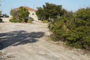 A house with a dirt driveway and surrounding greenery. - Baldwin Camp Rental Properties House #2, is located in North Caicos, TCI (North Caicos)