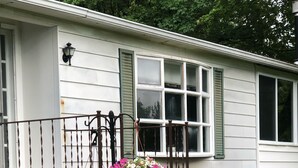 A house with a wooden staircase leading to a porch, surrounded by greenery and a flower planter. - Wine Country Getaway (Burdett)