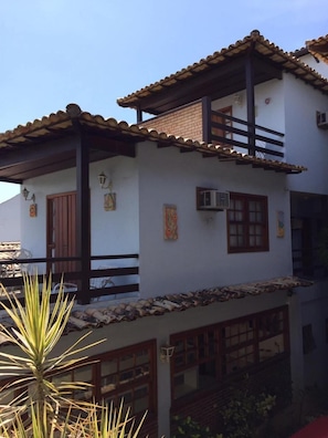 Un edificio de dos pisos con techo de tejas, balcones de madera y detalles decorativos en las paredes.