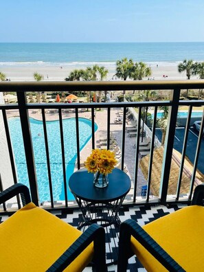 A balcony with a view of a pool and beach.