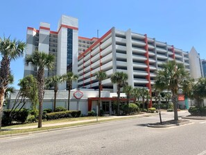 A multi-story hotel with a parking garage, palm trees, and a Starbucks.
