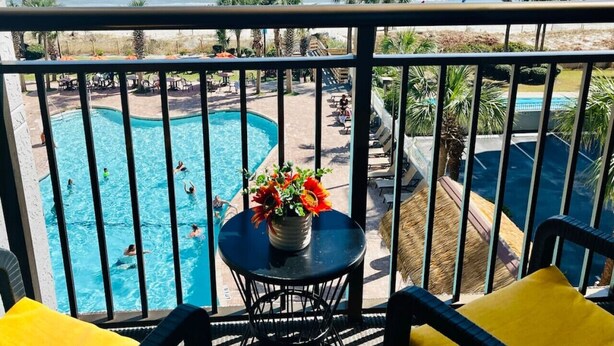 Ein Balkon mit Blick auf einen Swimmingpool und einen Strand.