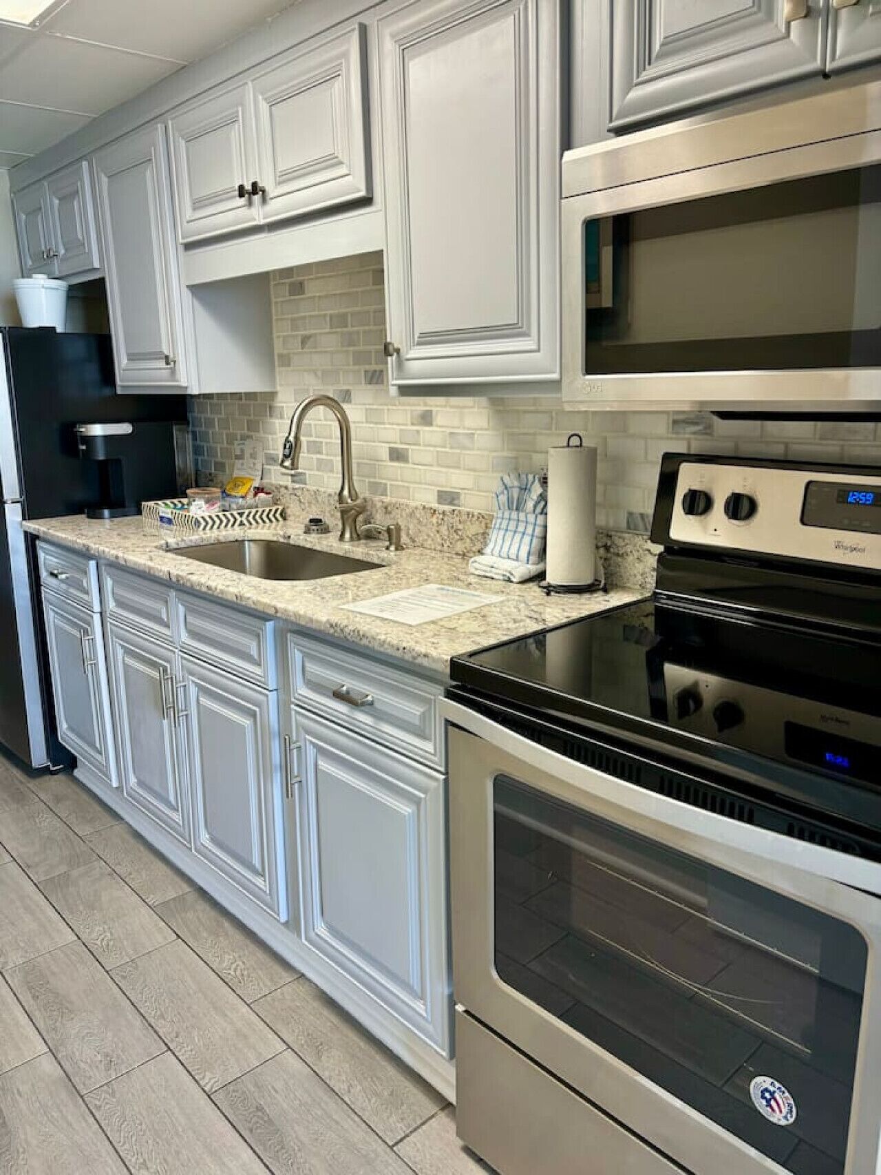 A kitchen with white cabinetry, a stainless steel refrigerator, a built-in oven, and a microwave.