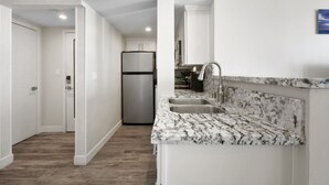 Een moderne keuken met een roestvrijstalen koelkast, een marmeren aanrechtblad en een spoelbak.