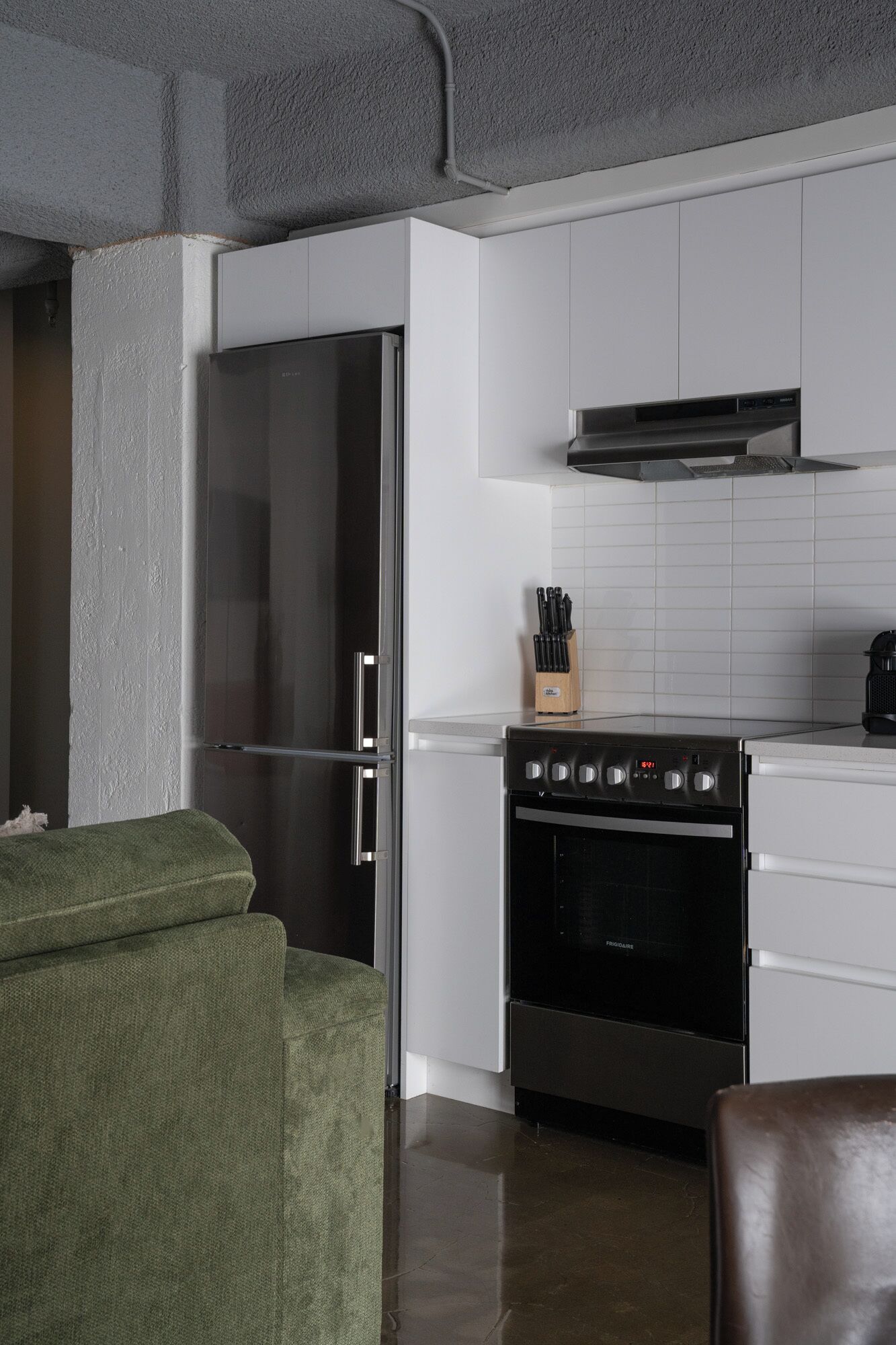 Una cocina moderna con armarios blancos, un refrigerador de acero inoxidable, un horno empotrado y una estufa a gas.
