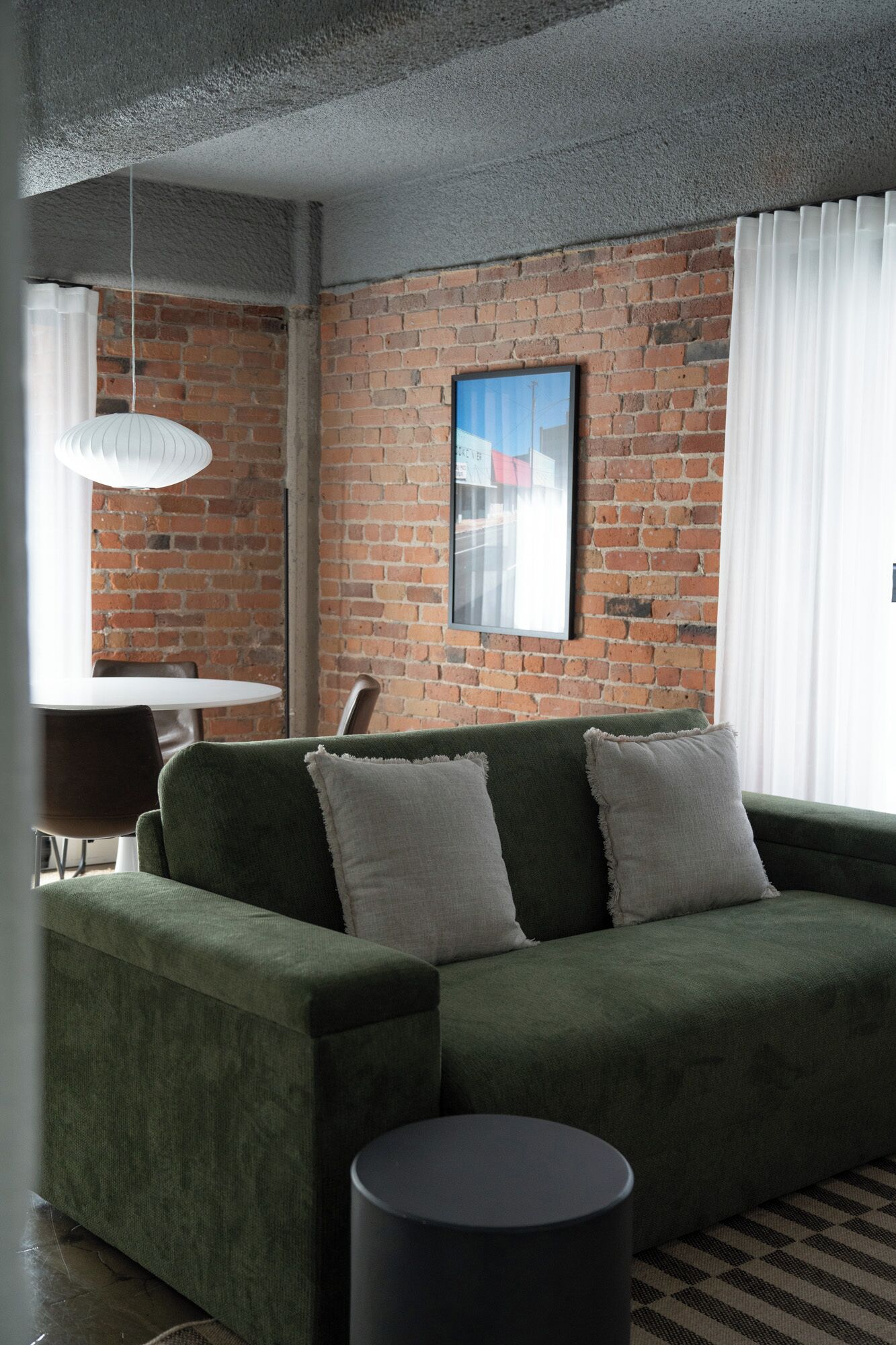 Una sala moderna con un sofá verde, una mesa de centro redonda y una pared de ladrillo.