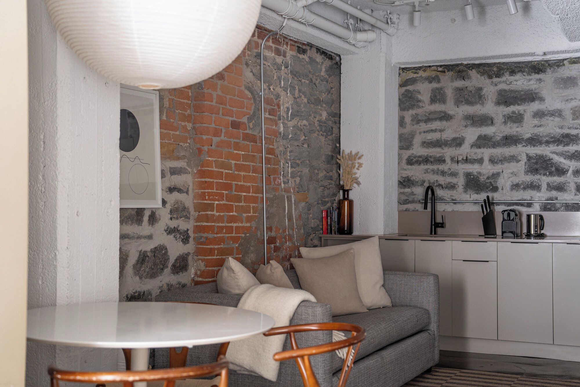 A compact kitchen with a brick wall, a white countertop, and a sink.