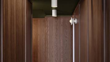 Un couloir avec des lambris en bois, un sol carrelé et des luminaires fixés au mur.