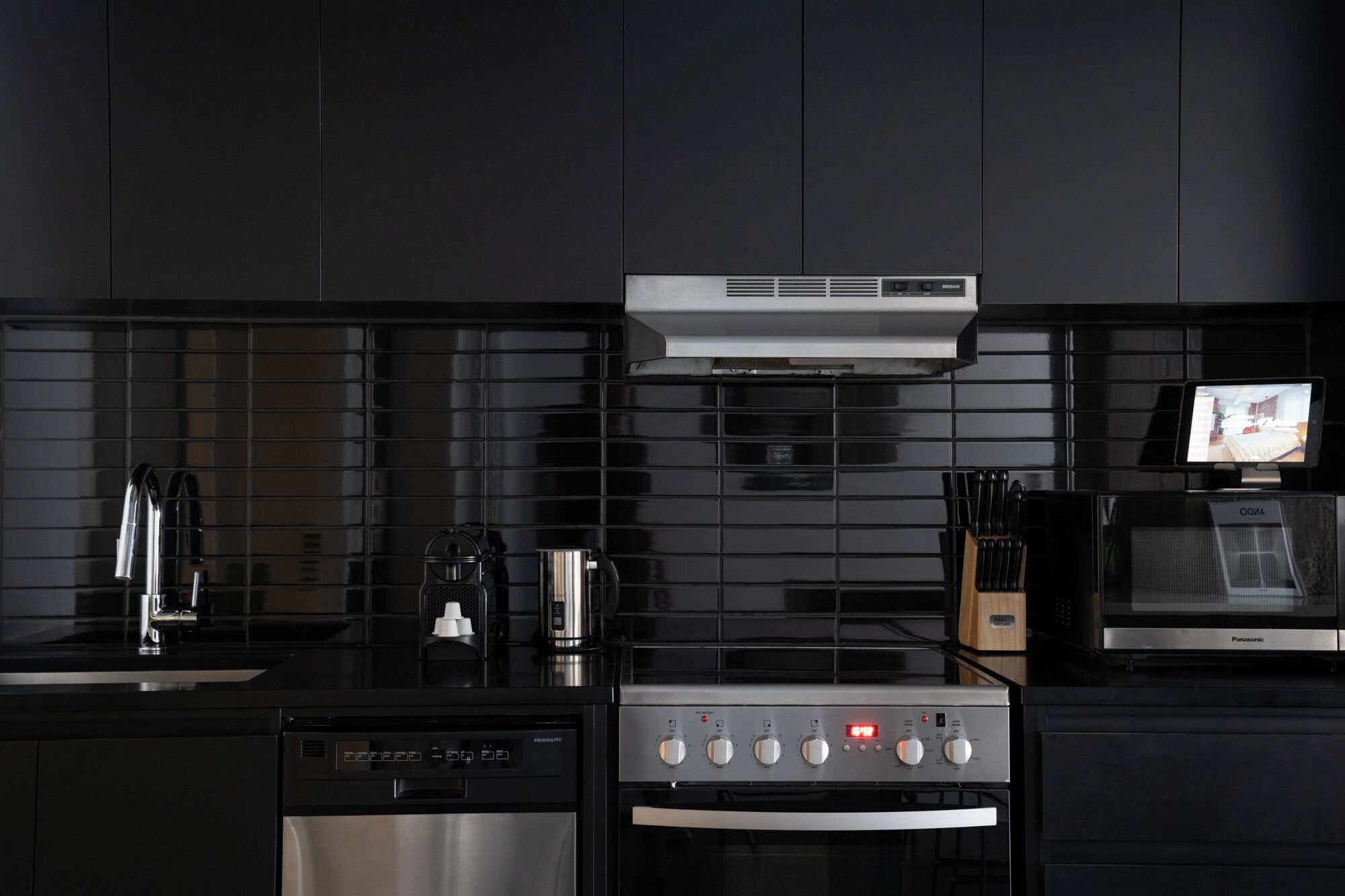 Una cocina moderna con lavavajillas integrado, horno, microondas y cafetera.