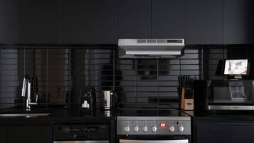 A modern kitchen with a built-in dishwasher, oven, microwave, and a coffee maker.