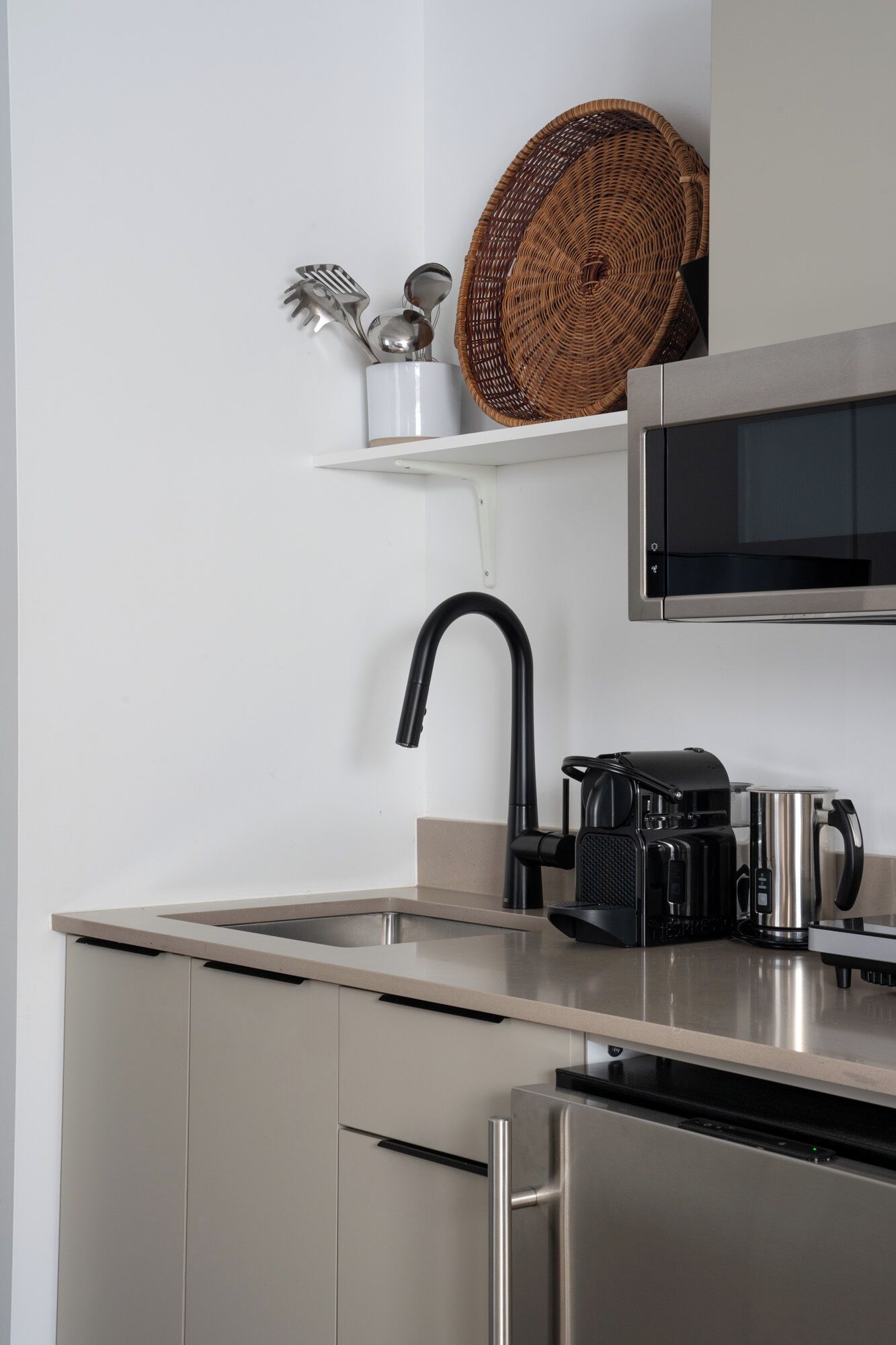 Una cocina moderna con electrodomésticos de acero inoxidable, un grifo negro, un microondas y una cafetera en la encimera.
