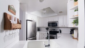 A modern kitchen with white cabinetry, stainless steel appliances, a built-in oven, and a white sink.