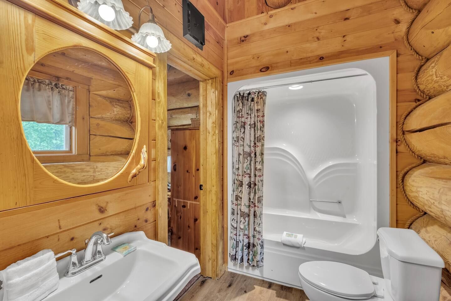 A wooden cabin bathroom with a sink, toilet, and bathtub.