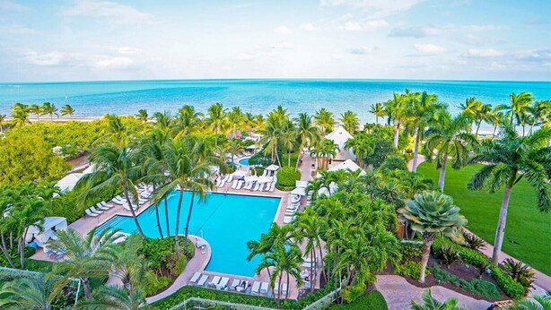Ein Resort mit Schwimmbad, Palmen und Blick aufs Meer.