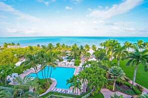 Un complexe hôtelier doté d’une piscine, de palmiers et offrant une vue sur l’océan.