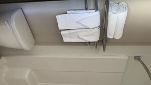 Une salle de bain équipée d’une baignoire, de toilettes et d’un porte-serviettes avec des serviettes pliées.