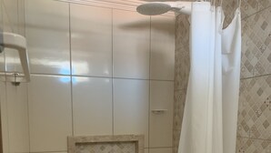 A bathroom with white tiles, a shower curtain, and a toilet.