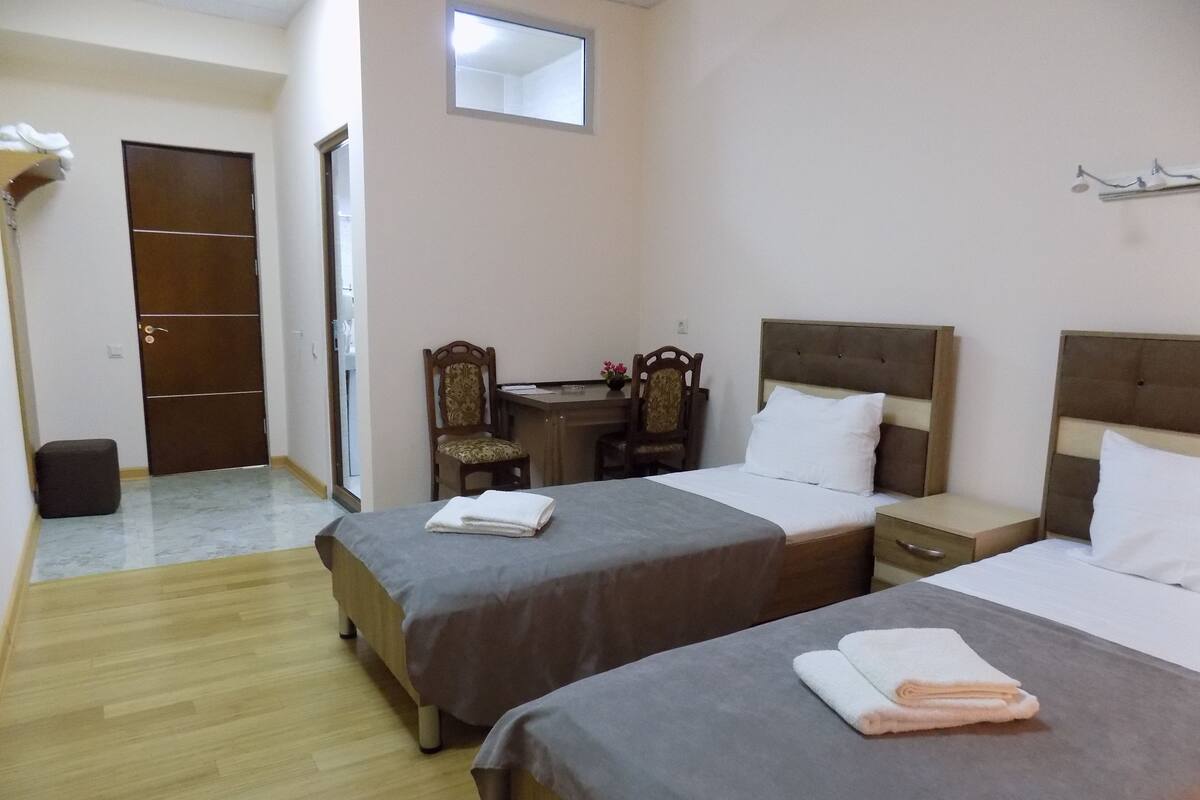 Ein Hotelzimmer mit zwei Betten, einem Schreibtisch, einem Stuhl und einem Kleiderschrank.