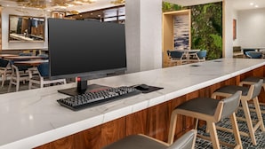 Zona de bar moderna con encimera de mármol, un televisor de pantalla plana grande, un teclado y taburetes de bar.