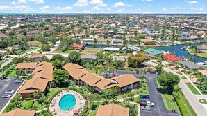 An aerial view of a residential area with a swimming pool, multiple buildings, and a marina.