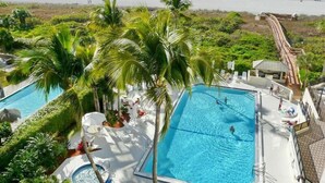 A resort with multiple swimming pools surrounded by lush greenery, a beach in the background, and a water slide. - Sandcastle I-507 (Marco Island)