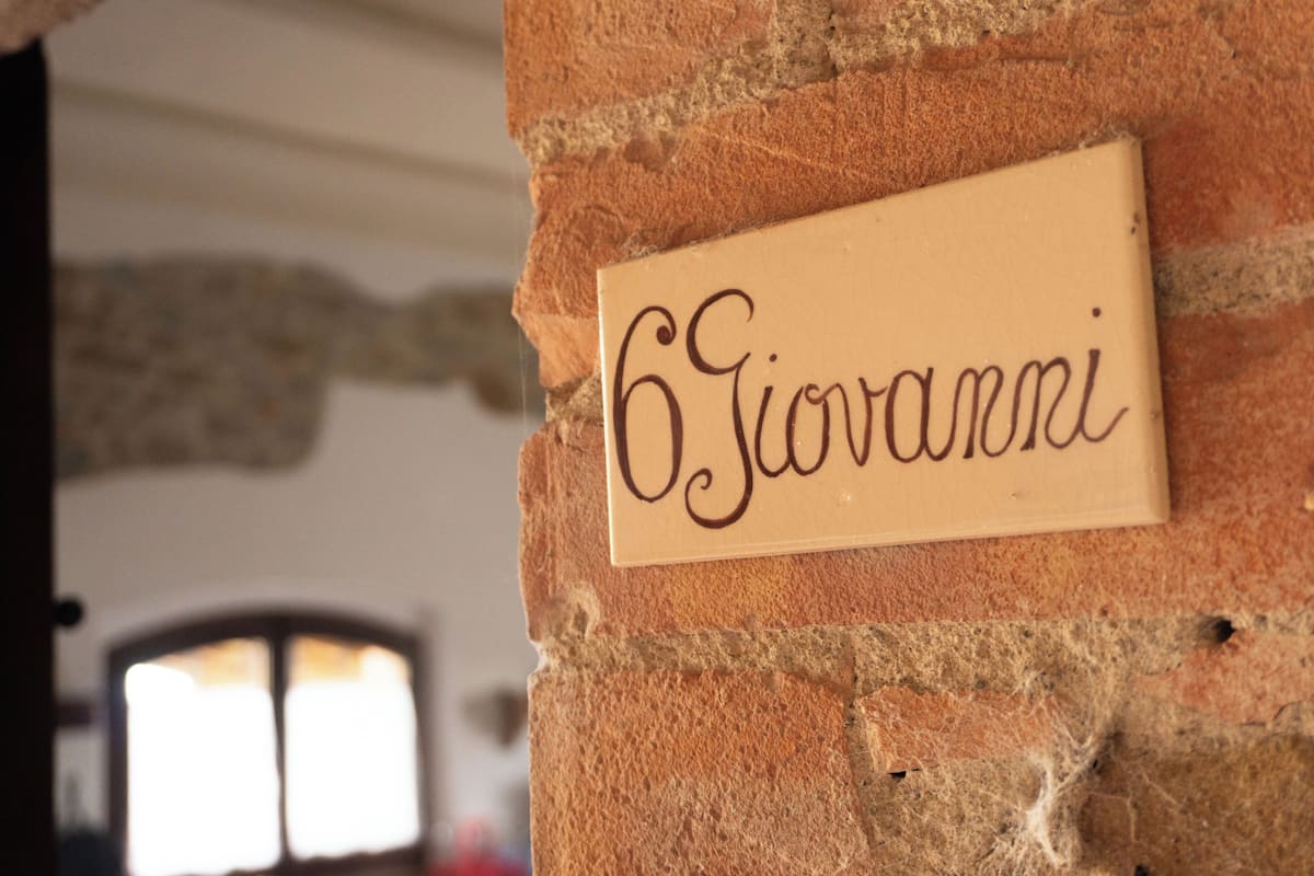 A sign with the name "Giovanni" on a brick wall.