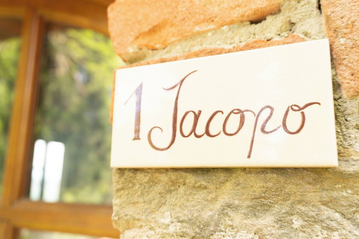 A stone wall with a nameplate reading "1 Jacopo".