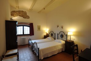 Two single beds with matching headboards and nightstands, each with a lamp, offer a comfortable space for rest. A large accent wall and wooden desk provide a functional area for work or study.