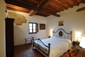Cozy retreat with a stone wall feature, wooden ceiling, and comfortable bed, complete with a bedside table and chair.
