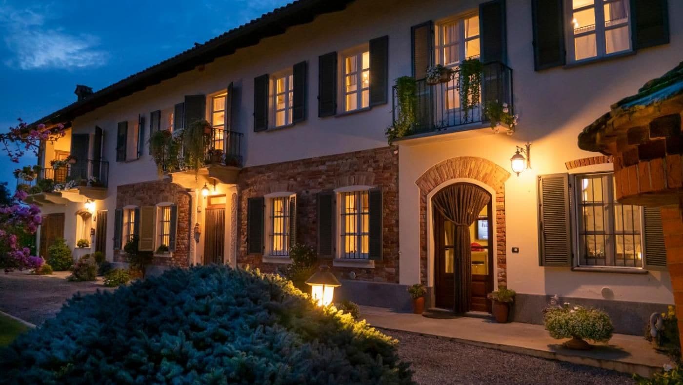 Un edificio a più piani con facciata in pietra, diverse finestre con persiane e un ingresso ben illuminato.