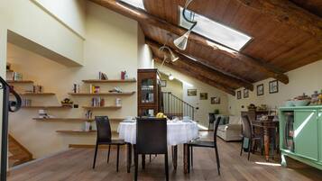 Un'area pranzo con soffitto in legno alto, una scala e un armadietto verde.